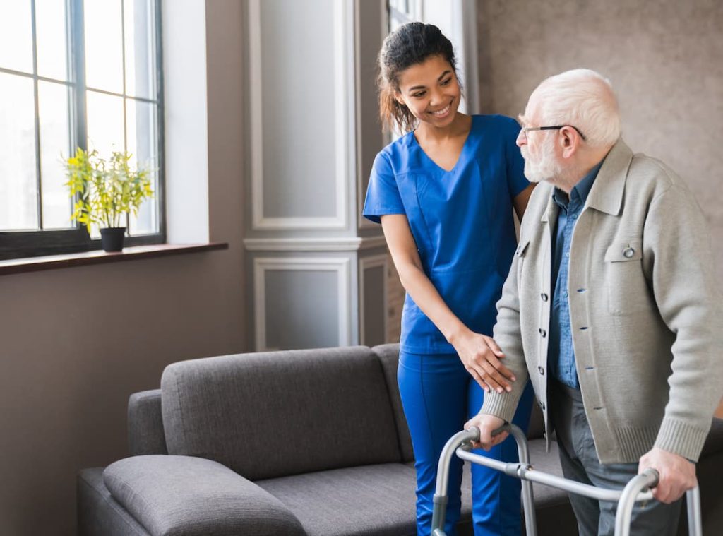 a nurse helping an old man with a walker