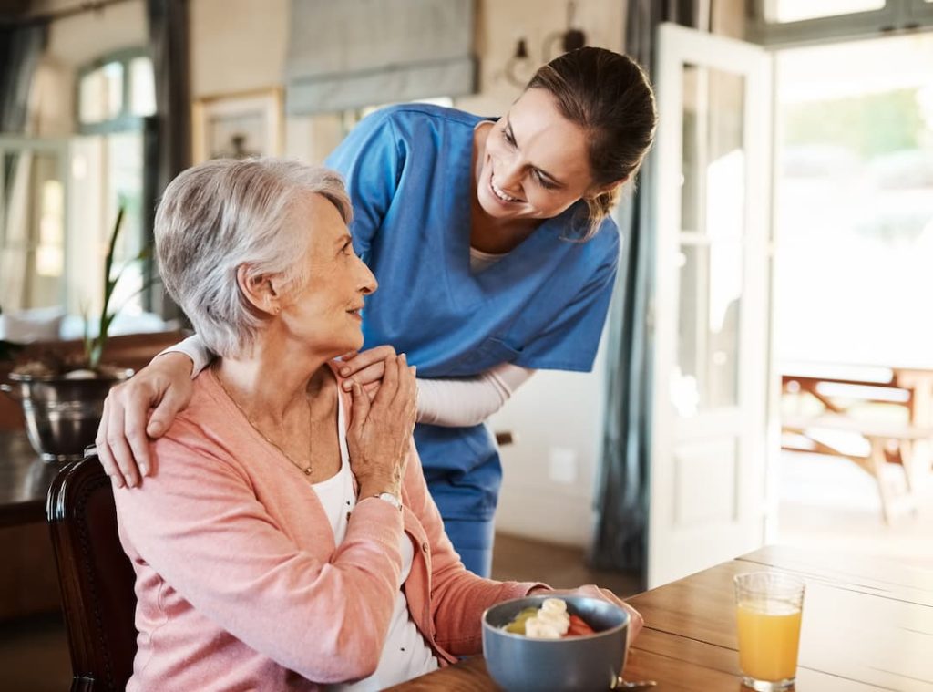 Healthcare, elderly woman with nurse with breakfast at her home and at the table in living room